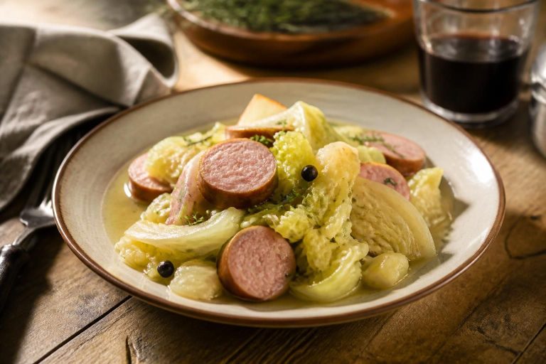 Saucisse de choux cuite pochée dans un bouillon fumant, servie avec des pommes de terre et des lentilles vertes du Puy dans une assiette rustique en grès